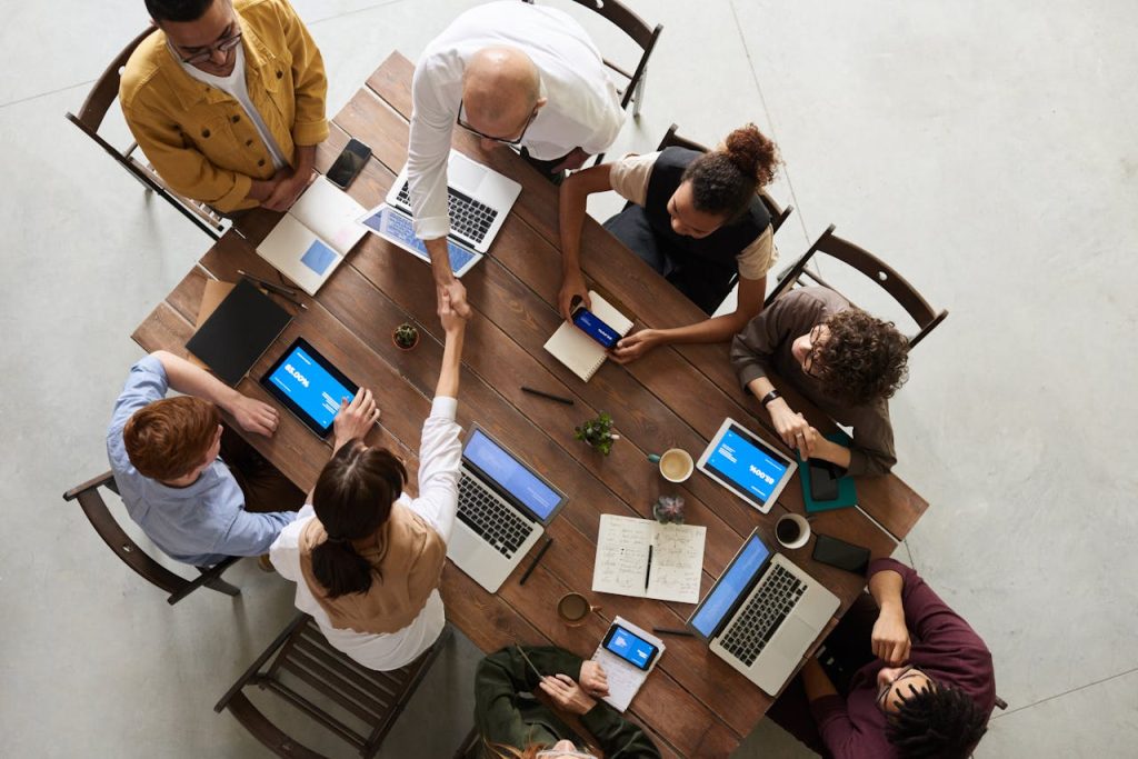 Top view of a diverse team collaborating in an office setting with laptops and tablets, promoting cooperation.